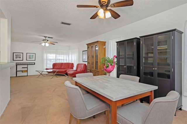 carpeted dining space featuring ceiling fan and a textured ceiling