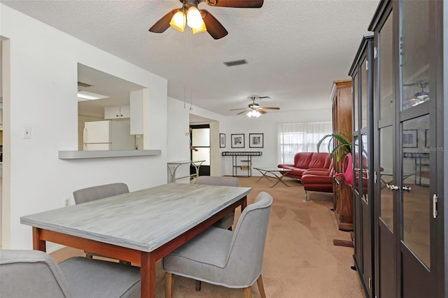 dining space featuring light carpet, a textured ceiling, and ceiling fan