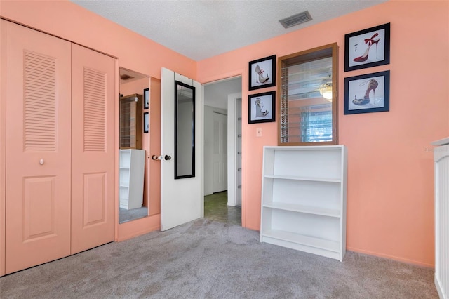 interior space with a closet, light carpet, and a textured ceiling