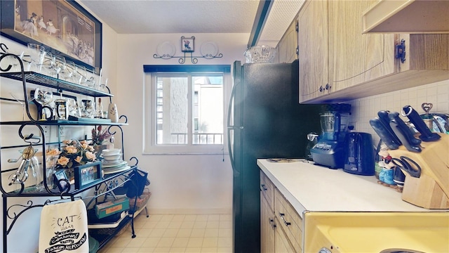 2205 Belleair Rd Unit A13, Clearwater, FL 33764 - kitchen featuring black refrigerator, a textured ceiling, light brown cabinetry, tasteful backsplash, and extractor fan