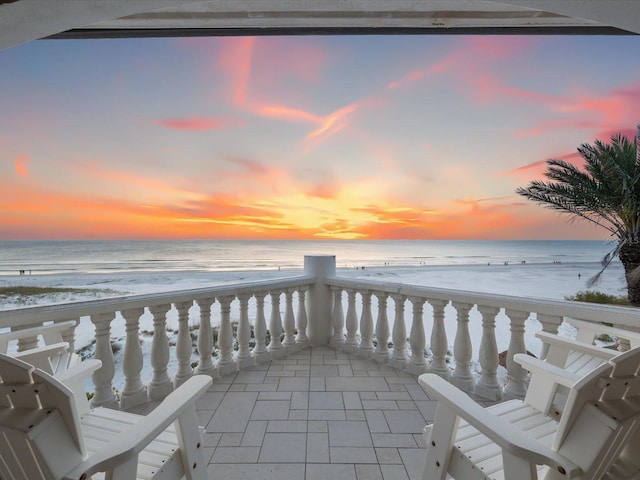 balcony at dusk featuring a water view