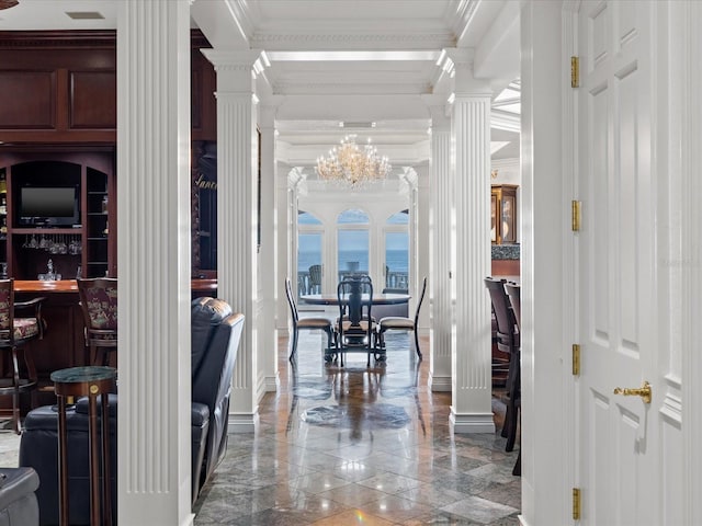 hall with decorative columns, a notable chandelier, tile floors, a water view, and crown molding