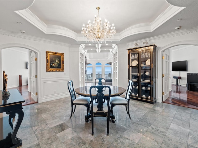 dining space featuring crown molding, a raised ceiling, an inviting chandelier, and light tile floors