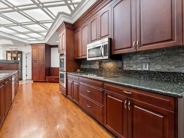 kitchen with stainless steel appliances, backsplash, dark stone countertops, light hardwood / wood-style flooring, and ornamental molding