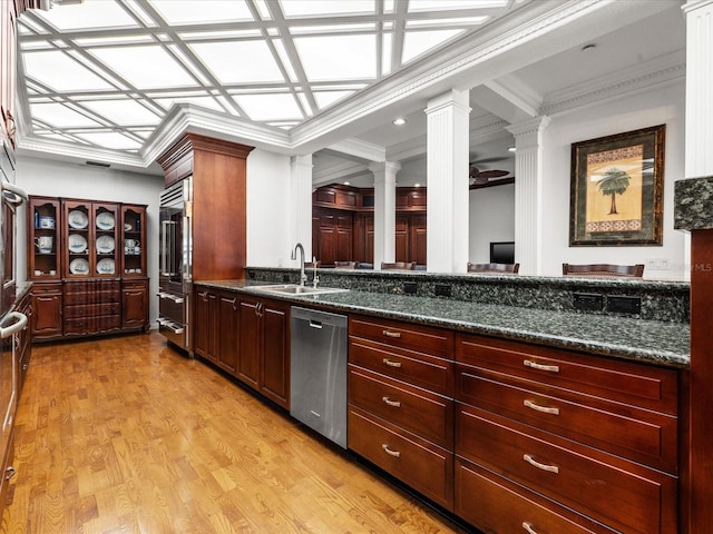 kitchen with ornate columns, stainless steel dishwasher, light hardwood / wood-style flooring, dark stone countertops, and sink