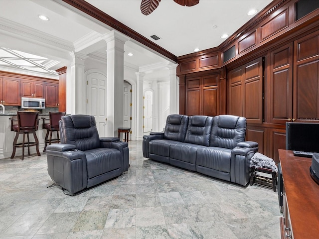 living room featuring ceiling fan, ornamental molding, light tile floors, and ornate columns