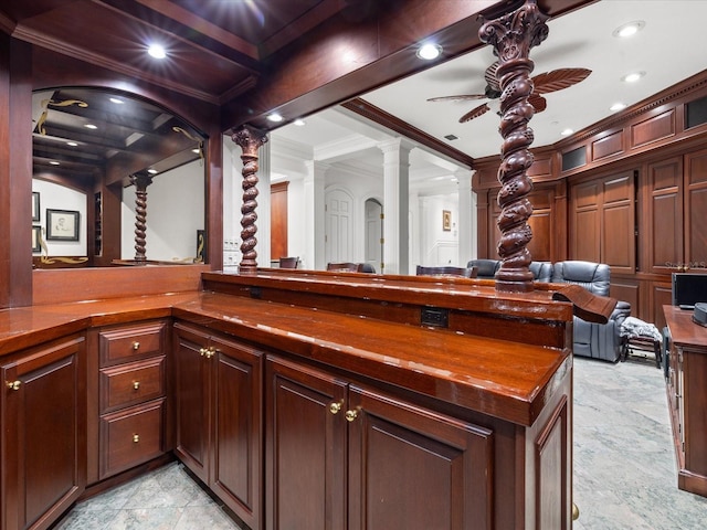 interior space with light tile flooring, ceiling fan, decorative columns, kitchen peninsula, and ornamental molding