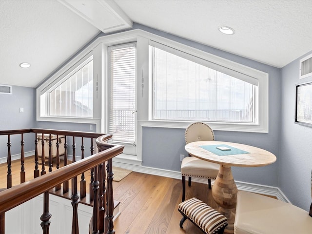 interior space with lofted ceiling, a textured ceiling, light wood-type flooring, and a healthy amount of sunlight