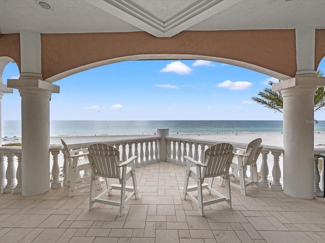 view of patio featuring a water view and a beach view