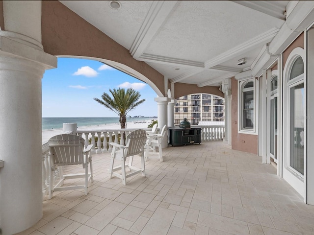 view of patio / terrace with a water view and a view of the beach