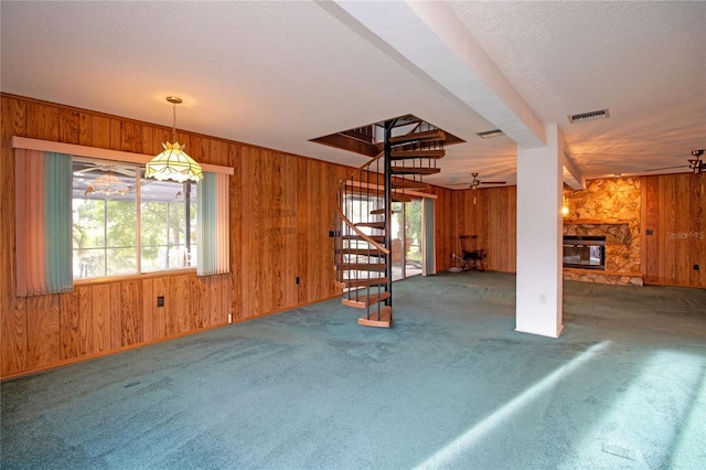 unfurnished living room featuring a fireplace, carpet, and wood walls