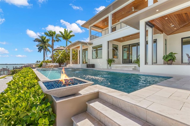 view of pool with an outdoor fire pit, pool water feature, and a patio