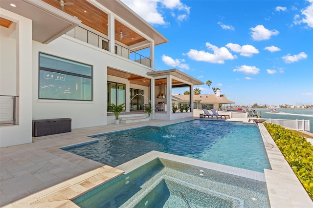 view of pool with an in ground hot tub, a water view, a patio, ceiling fan, and pool water feature