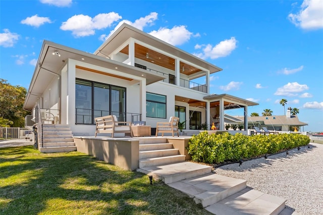 rear view of house featuring a balcony and a yard