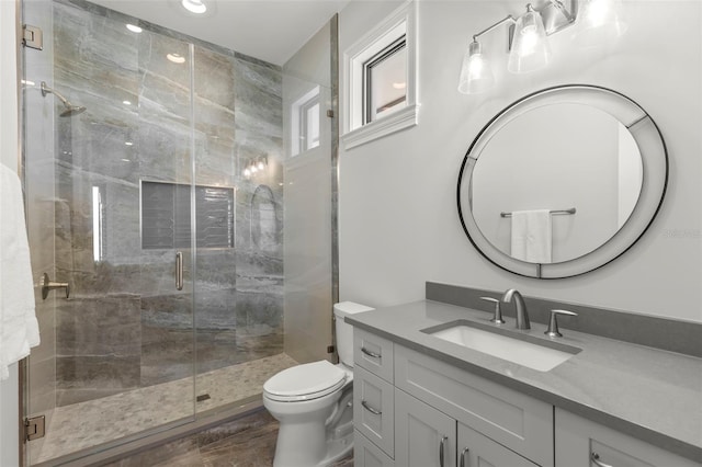 bathroom featuring vanity, a shower with shower door, and toilet