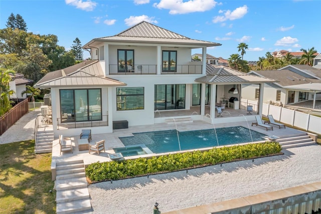 rear view of property with a balcony, a patio, pool water feature, and a fireplace