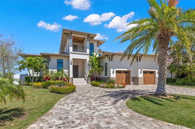 contemporary house with a balcony, a front yard, and a garage