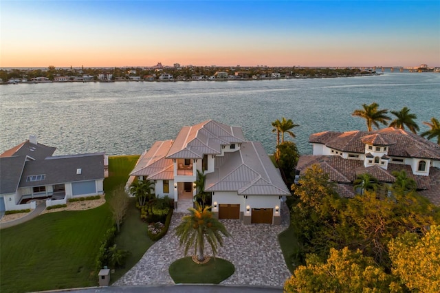 aerial view at dusk featuring a water view