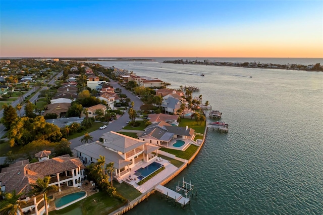 aerial view at dusk featuring a water view