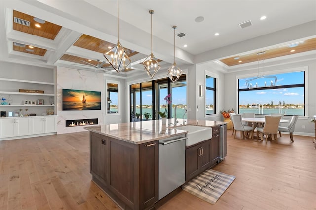 kitchen featuring decorative light fixtures, stainless steel dishwasher, sink, and dark brown cabinetry