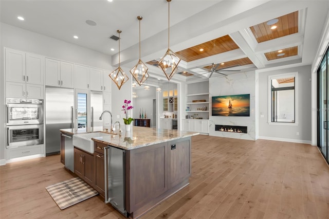 kitchen with pendant lighting, white cabinetry, sink, wooden ceiling, and coffered ceiling