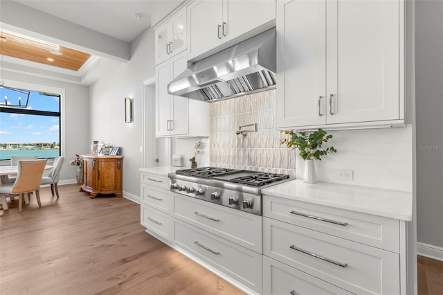 kitchen with stainless steel gas stovetop, white cabinets, a water view, ventilation hood, and light hardwood / wood-style floors