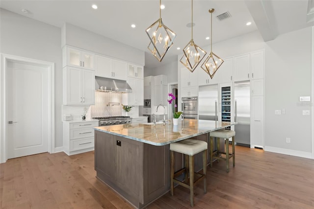 kitchen featuring sink, white cabinetry, and an island with sink