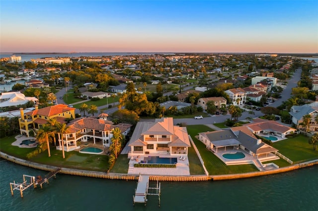 aerial view at dusk featuring a water view