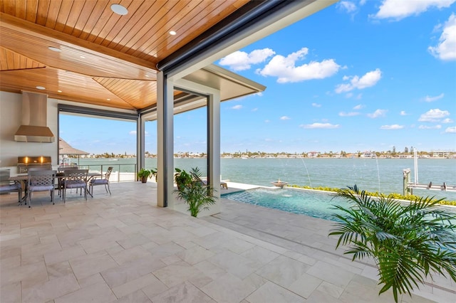 view of patio / terrace with a fireplace, pool water feature, a water view, and a grill