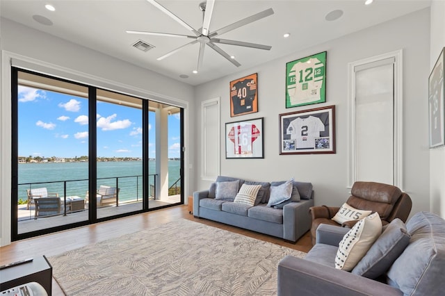 living room with ceiling fan, light hardwood / wood-style flooring, and a water view