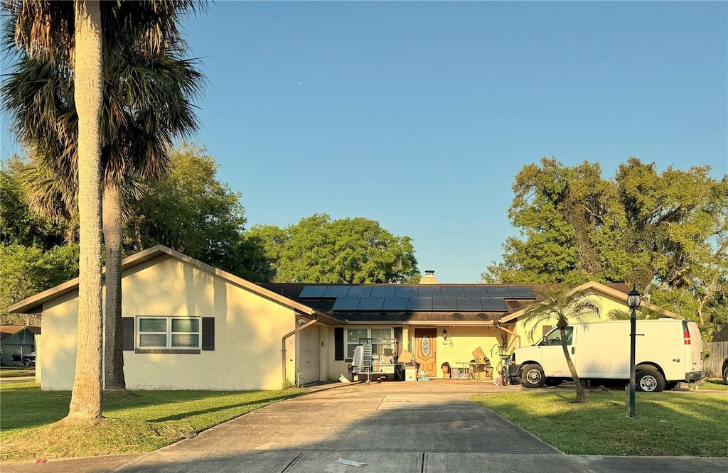 single story home with solar panels and a front lawn