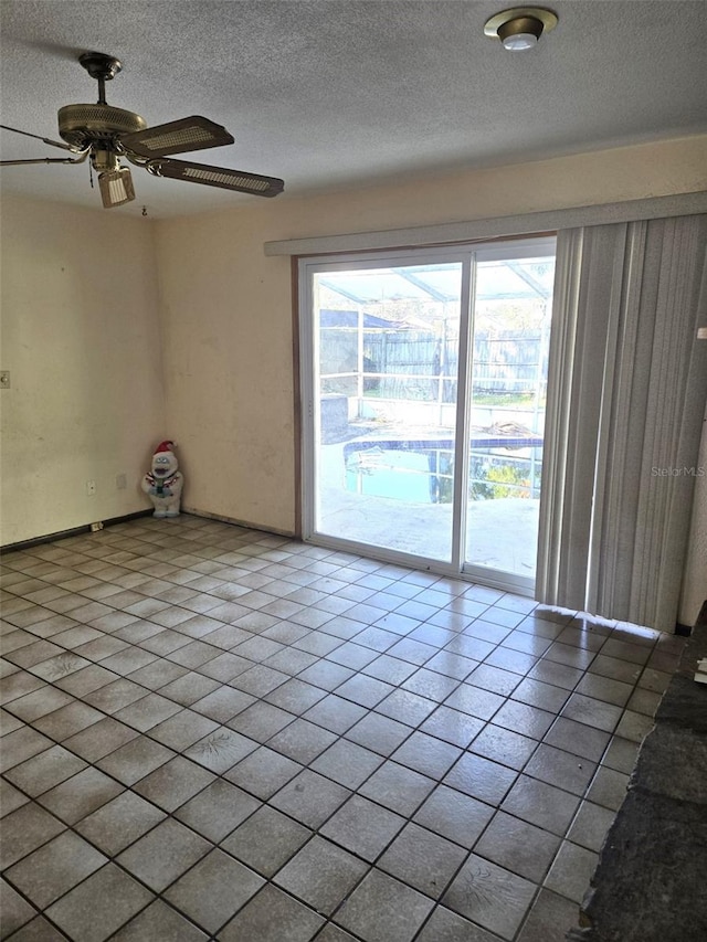 spare room with ceiling fan, a textured ceiling, and tile patterned flooring