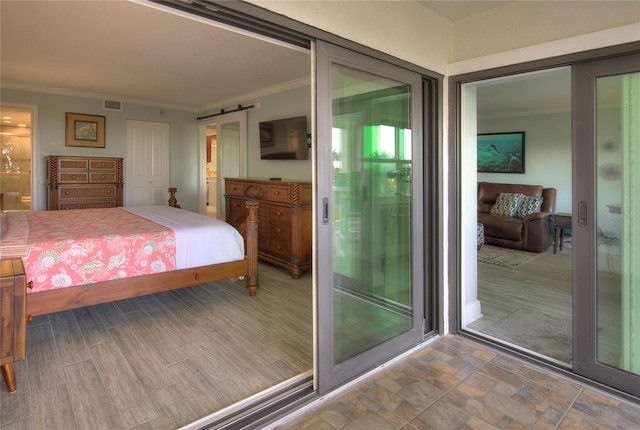 bedroom with connected bathroom, a barn door, access to outside, a closet, and ornamental molding