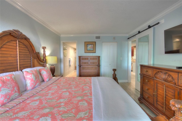 bedroom featuring light hardwood / wood-style flooring, a barn door, crown molding, and a closet