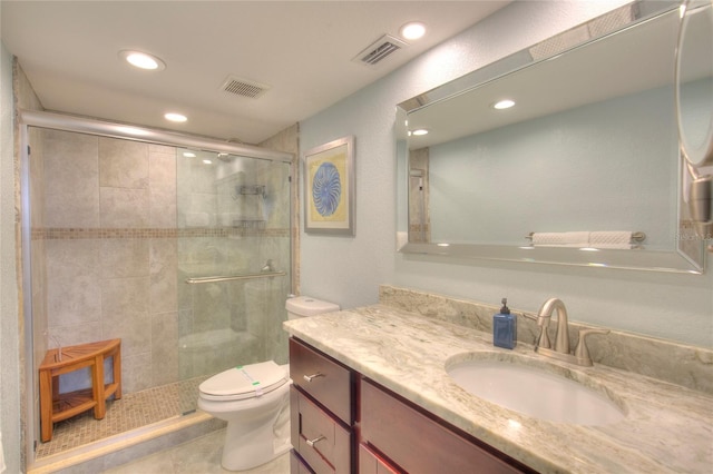 bathroom featuring tile patterned floors, vanity, toilet, and a shower with door