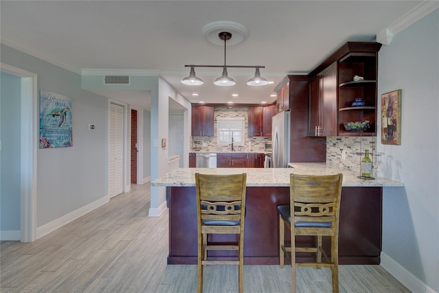 kitchen featuring decorative light fixtures, light stone countertops, kitchen peninsula, and ornamental molding