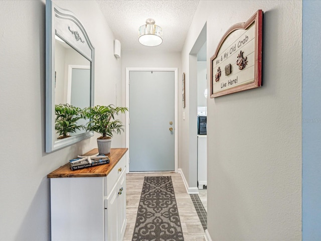 doorway to outside featuring light wood-type flooring and a textured ceiling