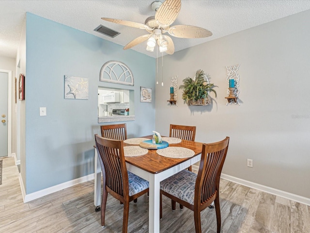 dining room featuring light hardwood / wood-style flooring, ceiling fan, and a textured ceiling