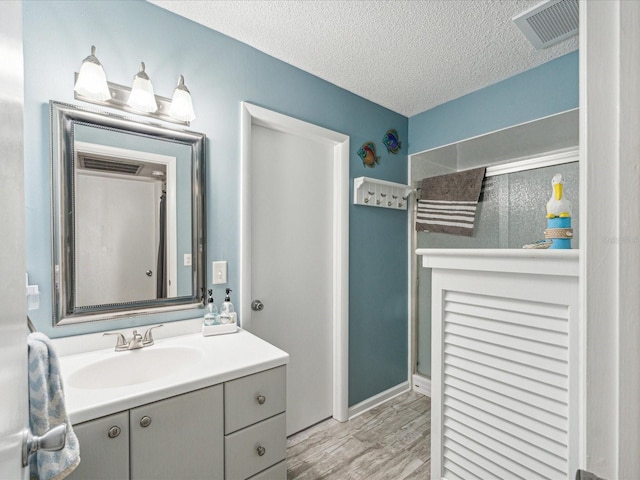 bathroom featuring wood-type flooring, large vanity, and a textured ceiling