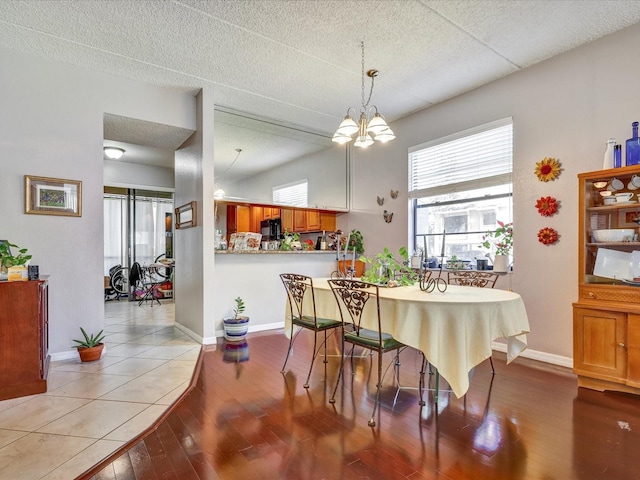 tiled dining area featuring an inviting chandelier and a textured ceiling