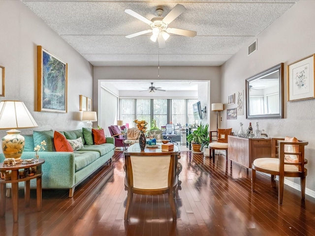 living room with ceiling fan, a textured ceiling, and dark wood-type flooring