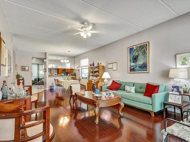 living room featuring a textured ceiling, ceiling fan with notable chandelier, and dark hardwood / wood-style flooring