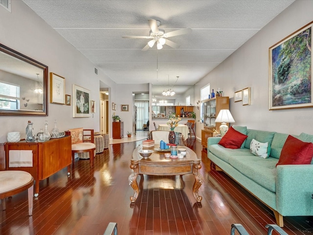 living room featuring ceiling fan with notable chandelier, a textured ceiling, and dark hardwood / wood-style flooring