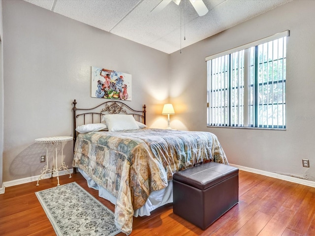 bedroom with a textured ceiling, wood-type flooring, and ceiling fan