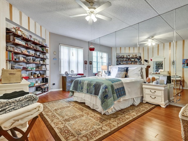 bedroom featuring ceiling fan, a paneled ceiling, light hardwood / wood-style flooring, and a textured ceiling