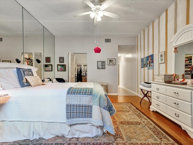 bedroom with ceiling fan, a textured ceiling, light hardwood / wood-style flooring, and a closet