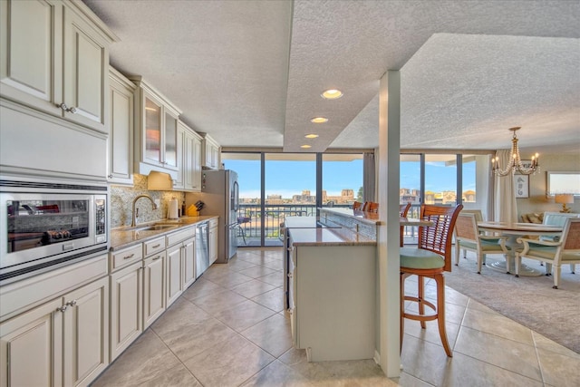 kitchen with hanging light fixtures, appliances with stainless steel finishes, a breakfast bar, a chandelier, and backsplash