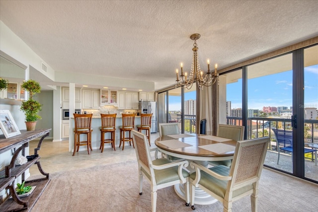 dining room with an inviting chandelier, a textured ceiling, light tile floors, and expansive windows