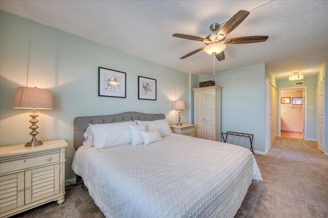 carpeted bedroom with connected bathroom, a textured ceiling, and ceiling fan