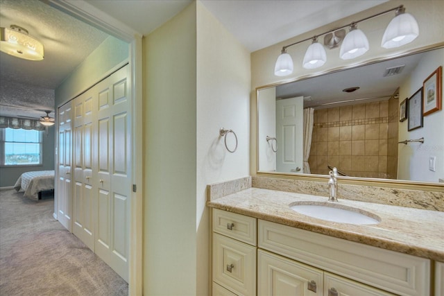 bathroom with a textured ceiling, ceiling fan, and large vanity